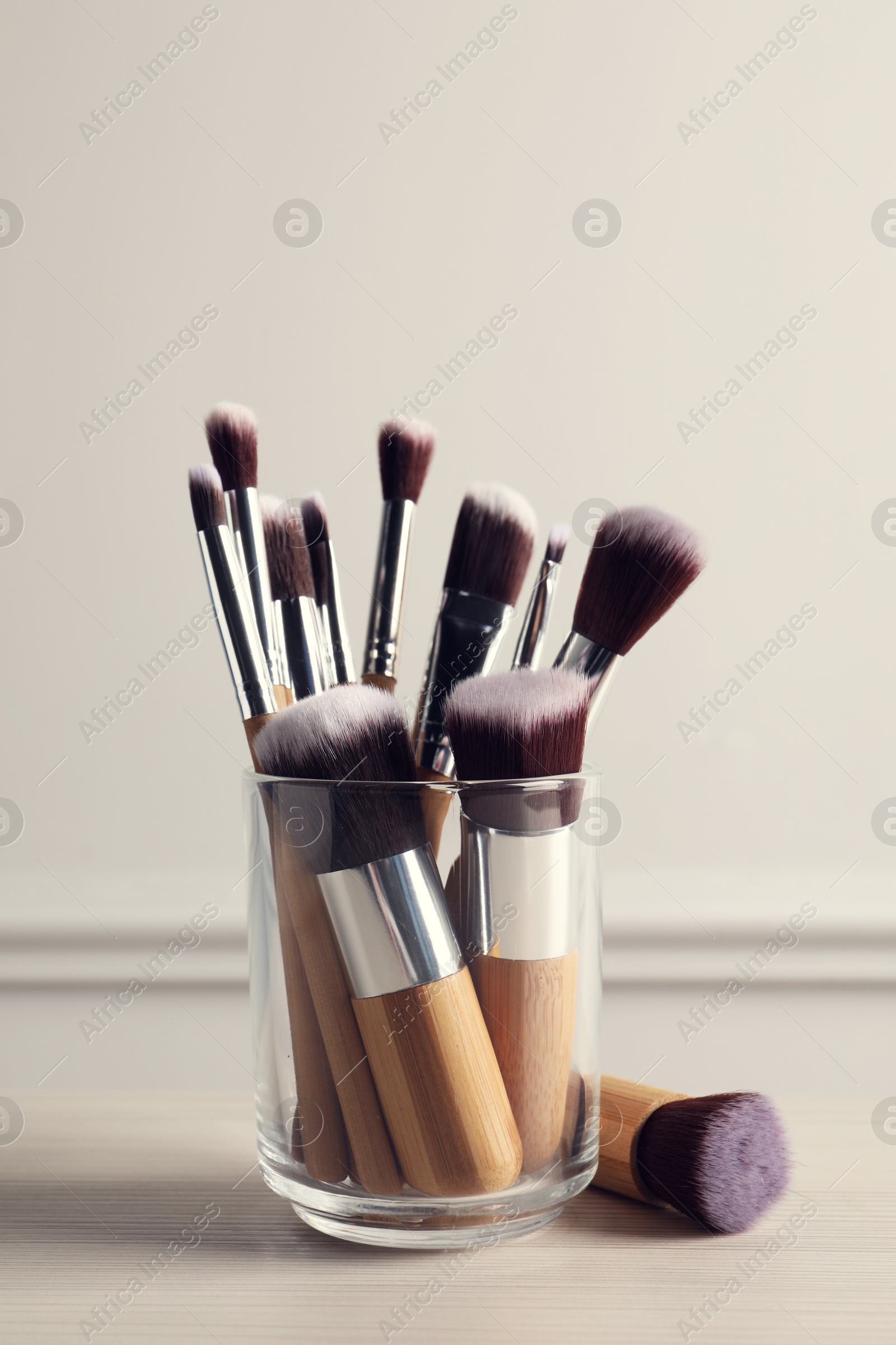 Photo of Set of professional makeup brushes on table against white background