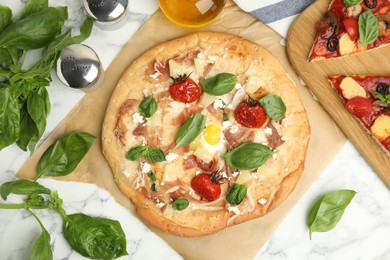 Delicious homemade pita pizza and basil on white marble table, flat lay
