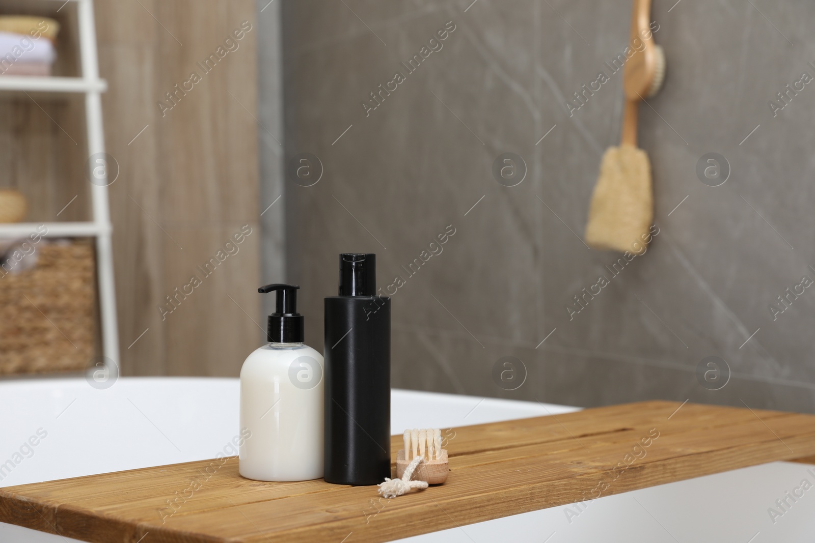 Photo of Wooden bath tray with bottles of shower gels and brush on tub indoors, space for text