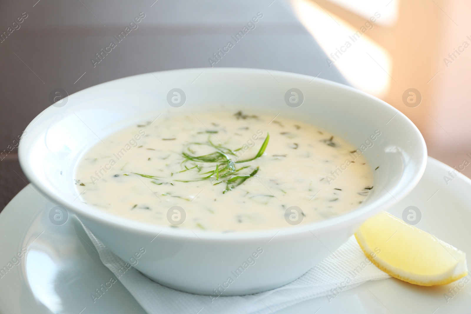 Photo of Delicious soup served with lemon slice, closeup