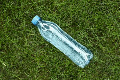 Bottle of fresh water on green grass, top view