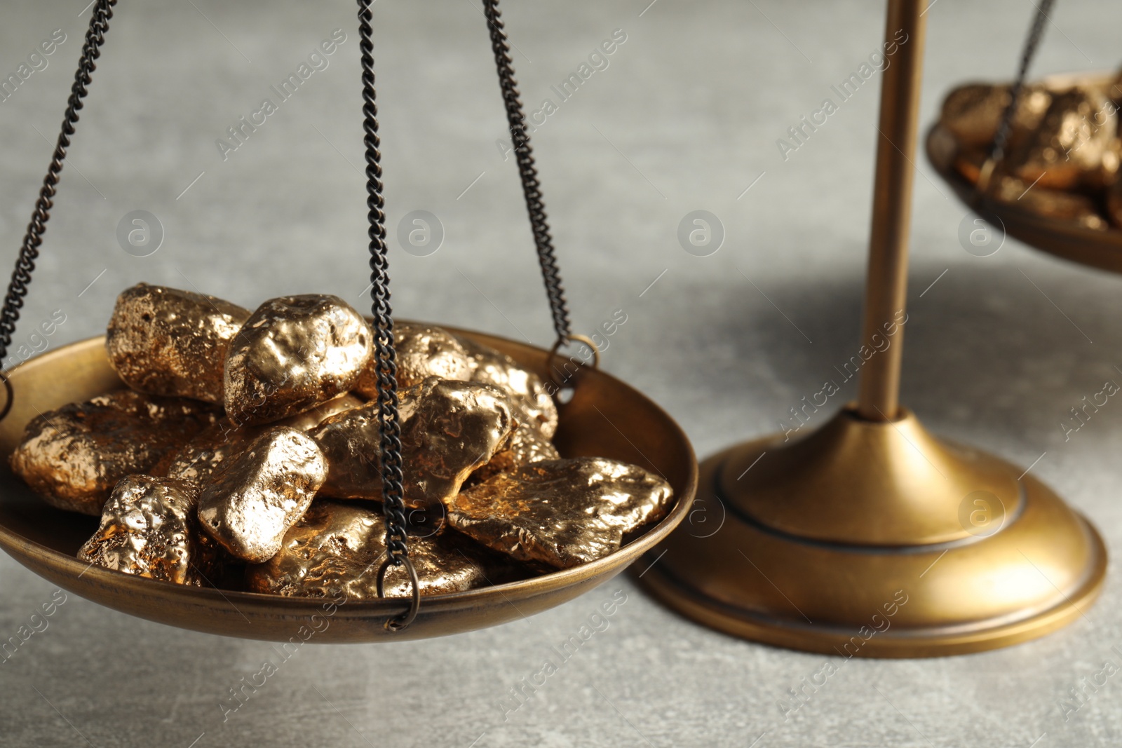 Photo of Vintage scales with gold nuggets on light grey table, closeup