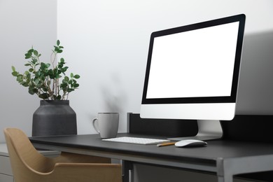 Modern computer with blank screen on black table indoors. Mockup for design