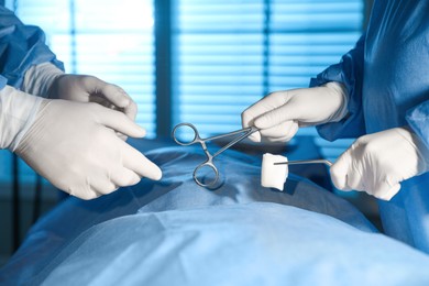 Photo of Professional surgeons with instruments performing operation in clinic, closeup
