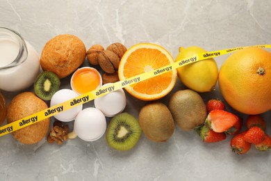 Photo of Allergenic food. Different fresh products with tape on gray marble table, top view