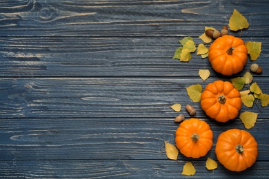 Photo of Flat lay composition with pumpkins and autumn leaves on blue wooden table. Space for text