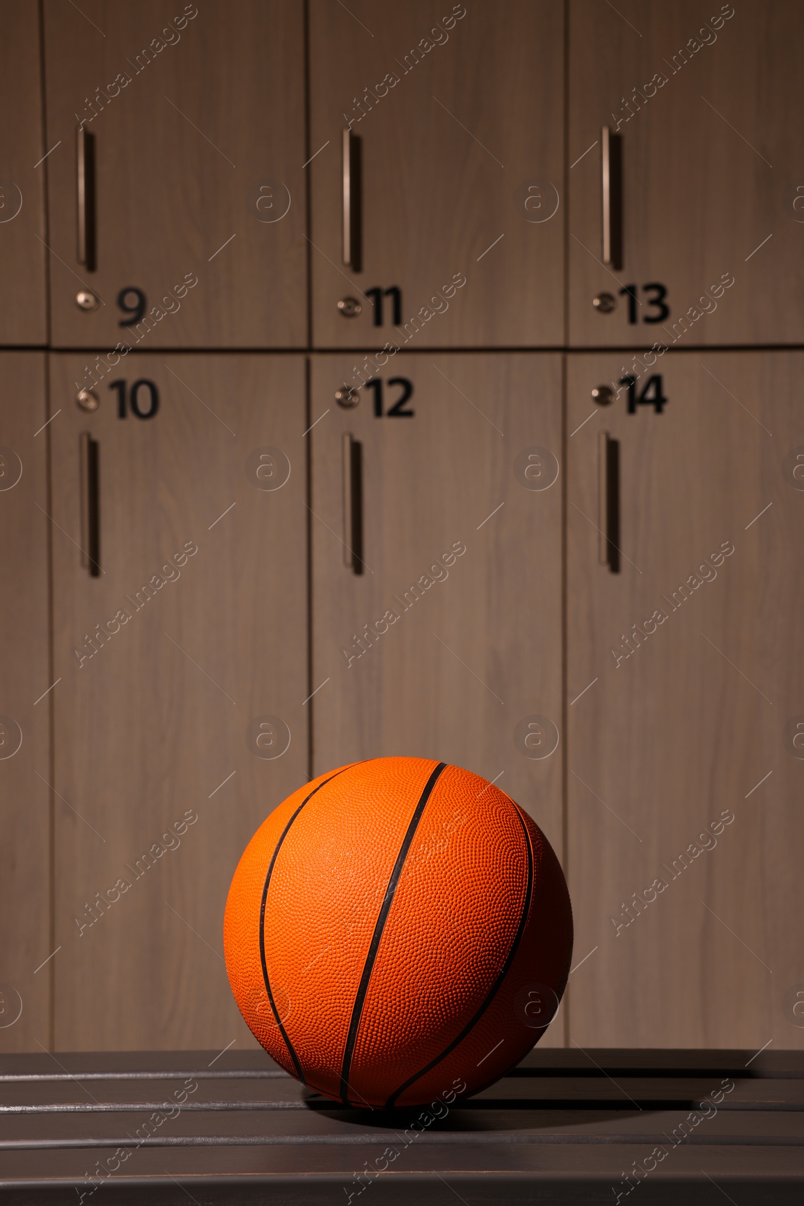 Photo of Orange basketball ball on wooden bench in locker room