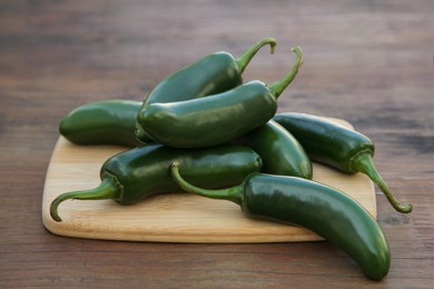 Photo of Fresh green jalapeno peppers on wooden table, closeup