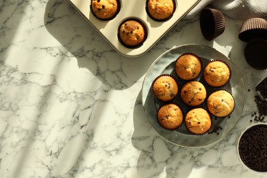 Photo of Delicious sweet muffins with chocolate chips on white marble table, flat lay. Space for text