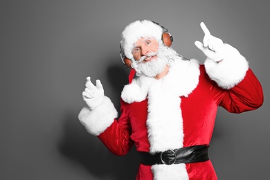 Santa Claus listening to Christmas music on color background