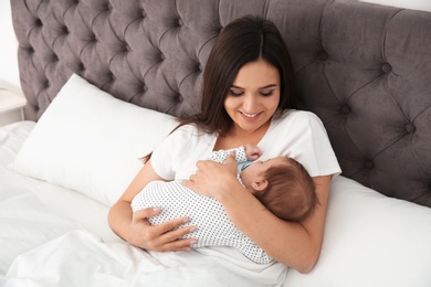 Photo of Happy woman holding her sleeping baby on bed