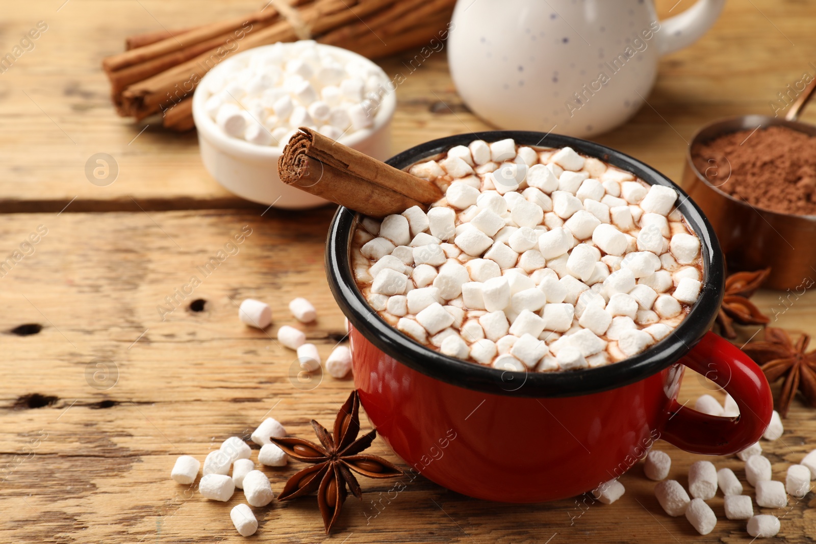 Photo of Tasty hot chocolate with marshmallows and ingredients on wooden table, closeup. Space for text