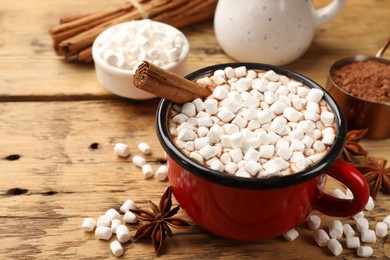 Photo of Tasty hot chocolate with marshmallows and ingredients on wooden table, closeup. Space for text