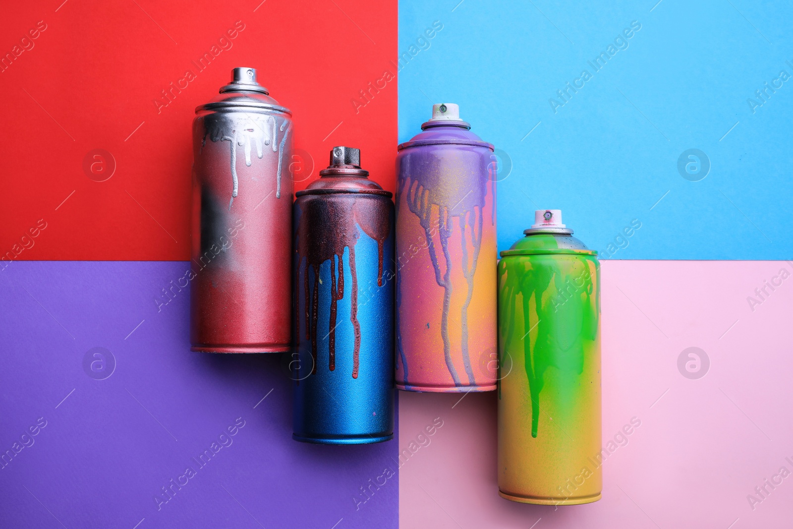 Photo of Used cans of spray paints on color background, flat lay. Graffiti supplies