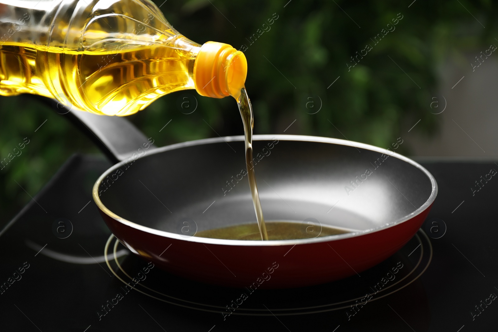 Photo of Pouring cooking oil from bottle into frying pan, closeup