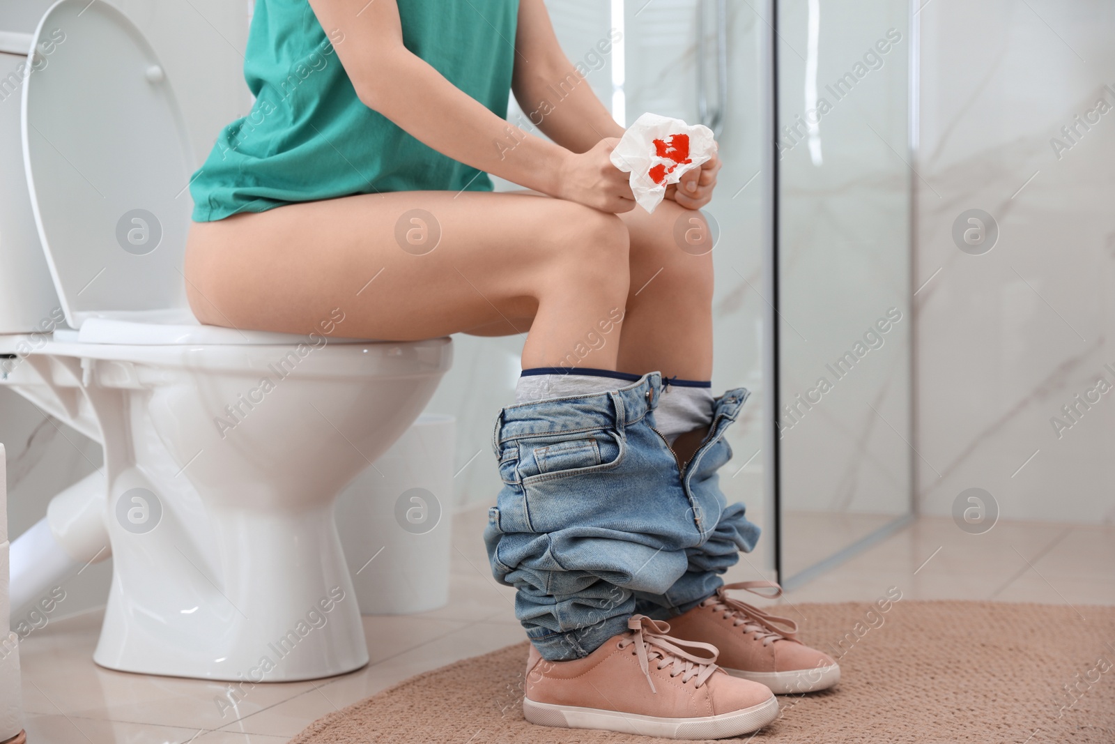 Photo of Woman holding toilet paper with blood stain in rest room, closeup. Hemorrhoid concept