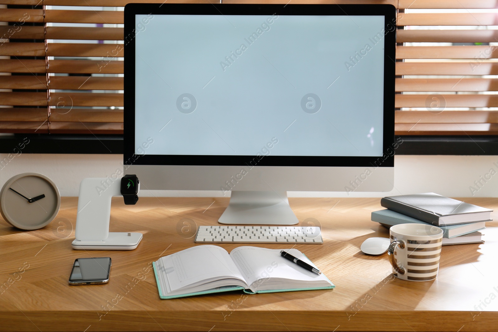 Photo of Modern workplace and watch charging with wireless pad