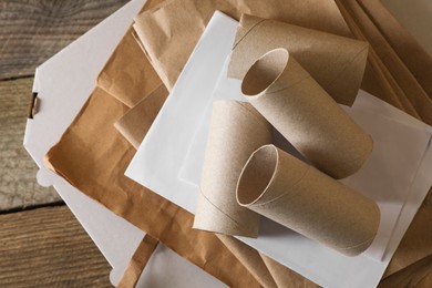 Stack of different waste paper on wooden table, flat lay