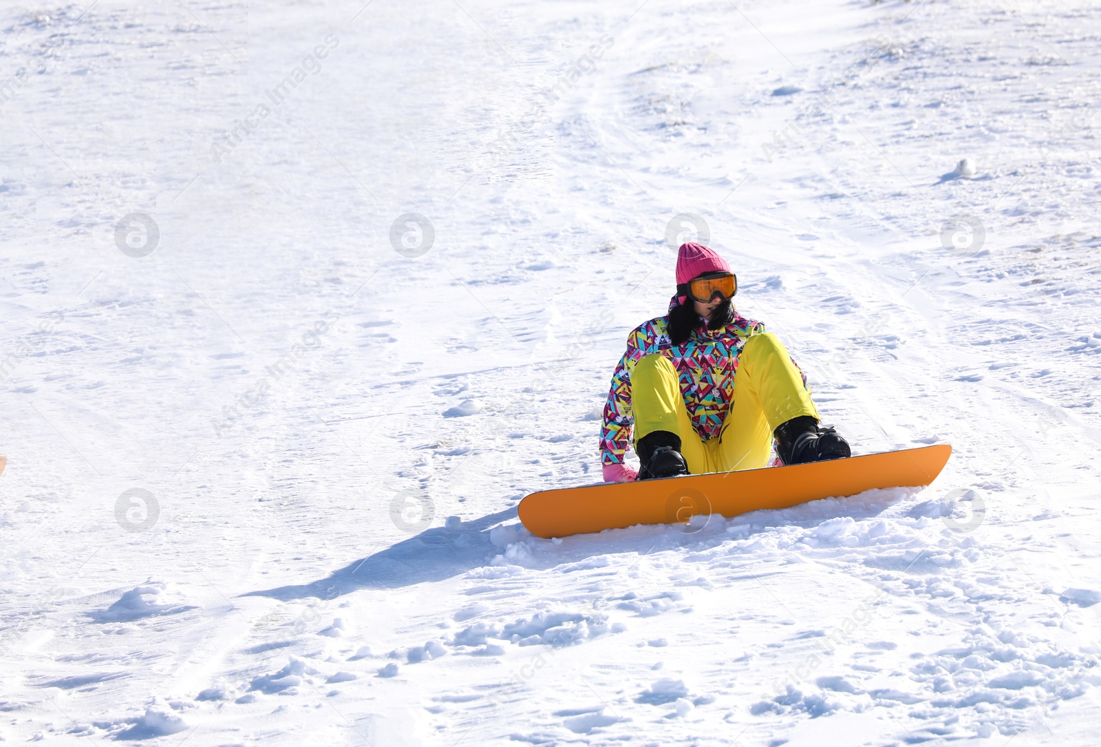 Photo of Young woman snowboarding on hill. Winter vacation