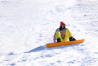 Photo of Young woman snowboarding on hill. Winter vacation