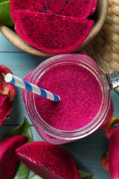 Photo of Delicious pitahaya smoothie in mason jar and fresh fruits on light blue wooden table, flat lay