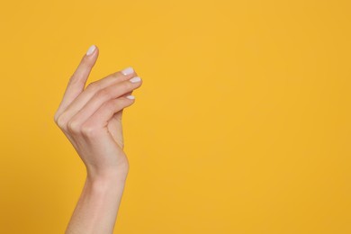 Photo of Woman holding something against yellow background, closeup on hand. Space for text