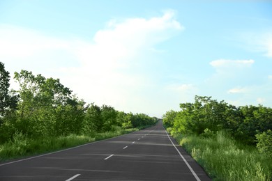 Asphalt road running through countryside on sunny day