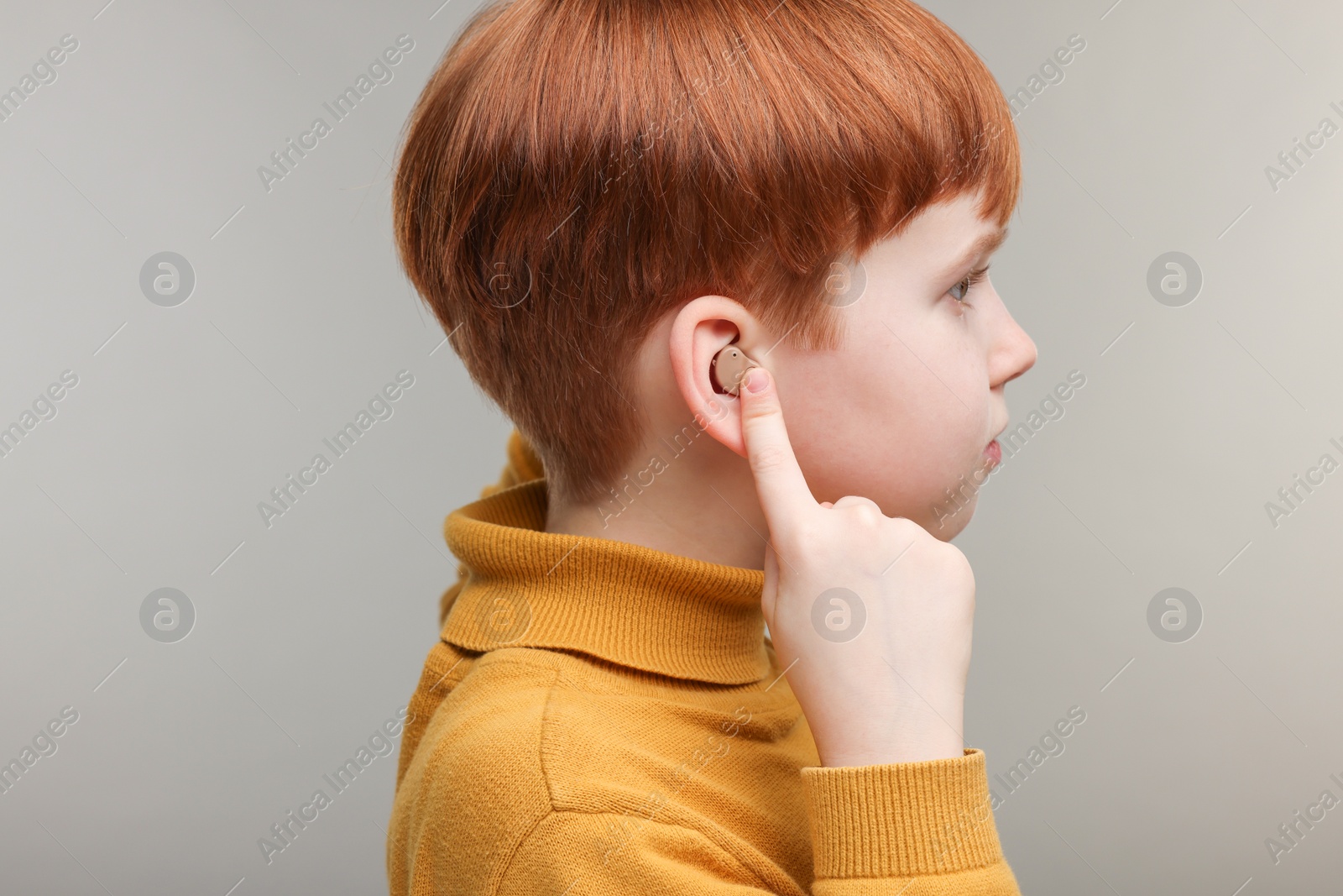 Photo of Little boy with hearing aid on grey background