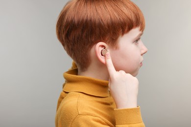 Photo of Little boy with hearing aid on grey background