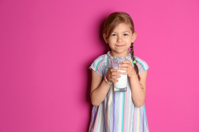 Photo of Cute little girl with glass of milk on color background