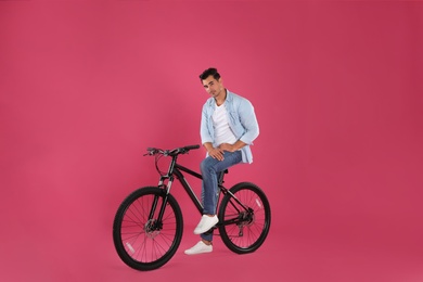 Photo of Handsome young man with modern bicycle on pink background