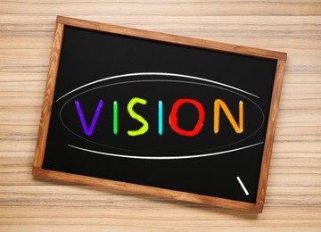 Small chalkboard with word Vision on wooden background, top view