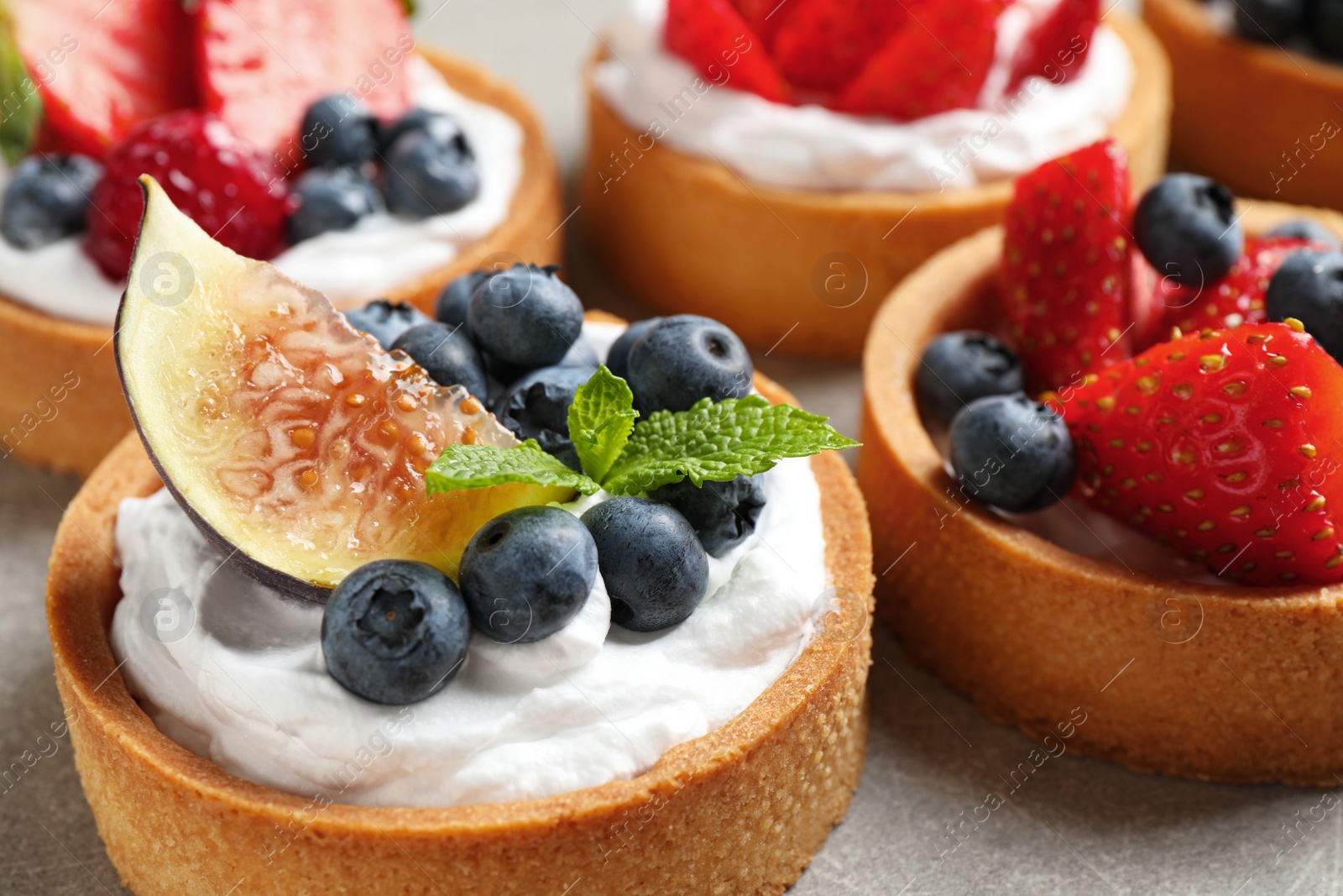 Photo of Delicious sweet pastries with berries on grey table, closeup