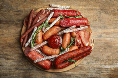 Different types of sausages with rosemary served on wooden table, top view