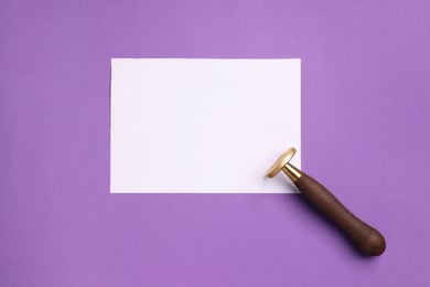Photo of One stamp tool and sheet of paper on purple background, top view. Space for text