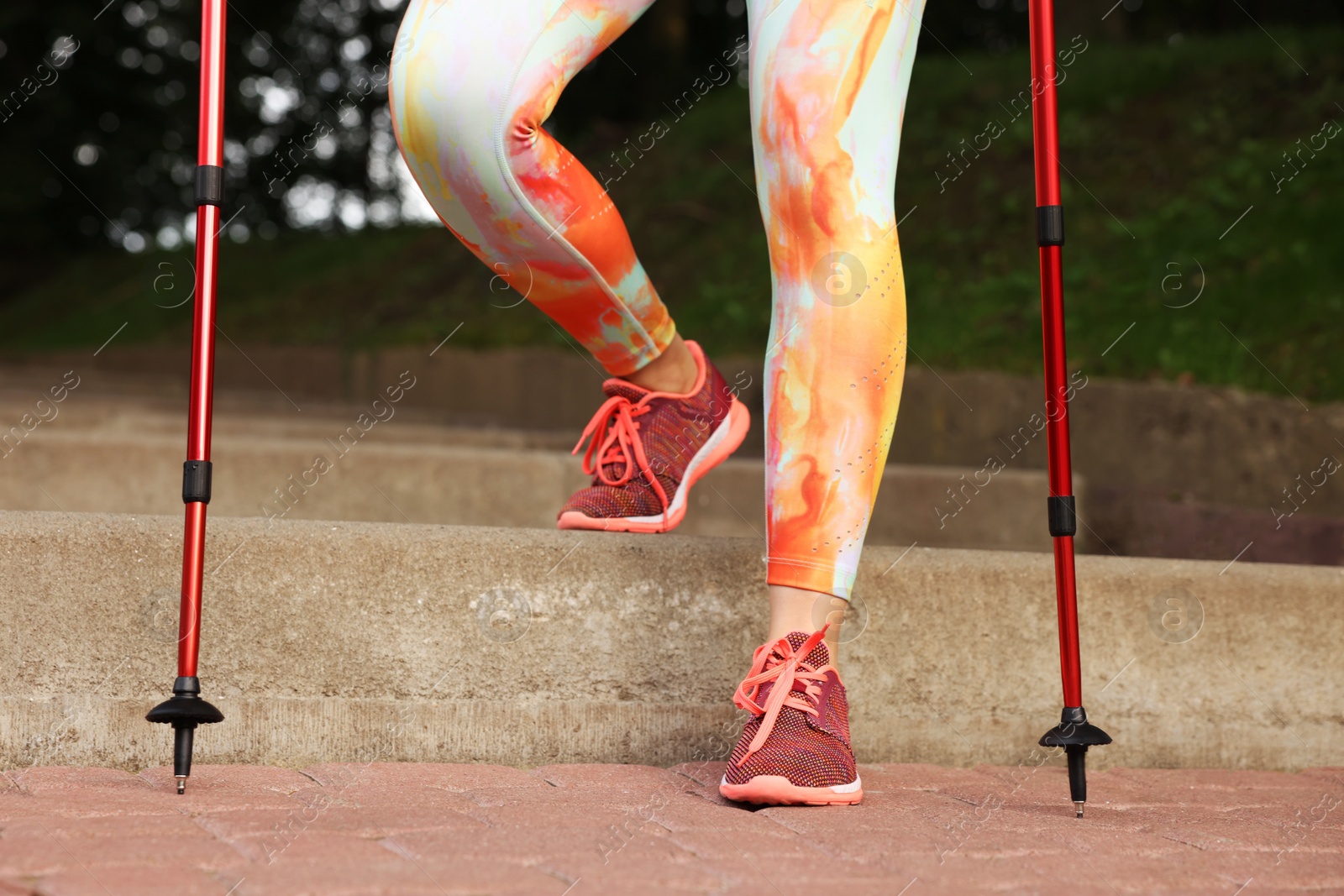 Photo of Young woman practicing Nordic walking with poles on steps outdoors, closeup