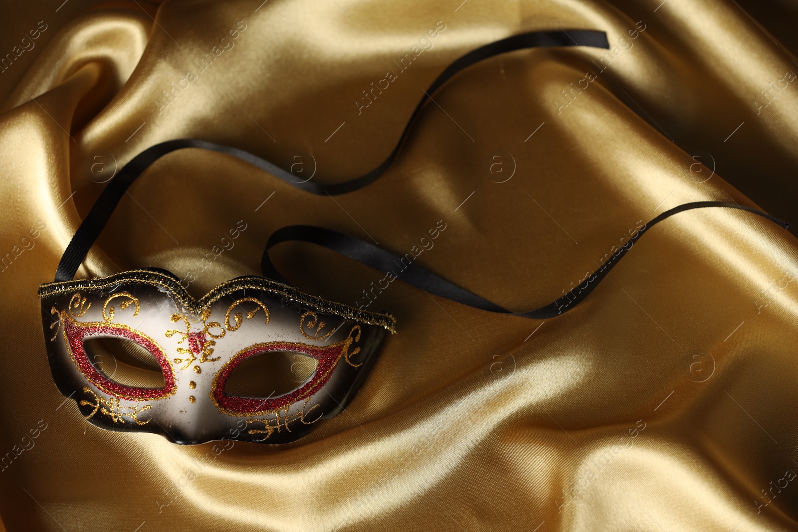 Photo of Elegant face mask on golden fabric. Theatrical performance