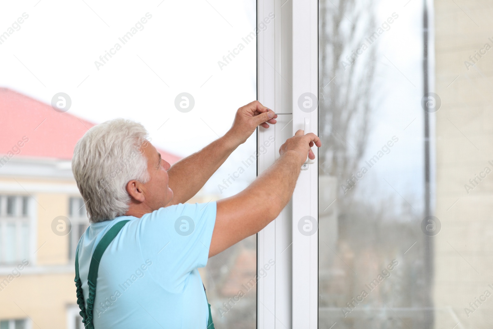 Photo of Mature construction worker repairing plastic window indoors