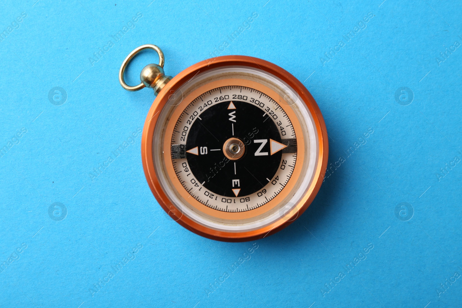 Photo of One compass on light blue background, top view