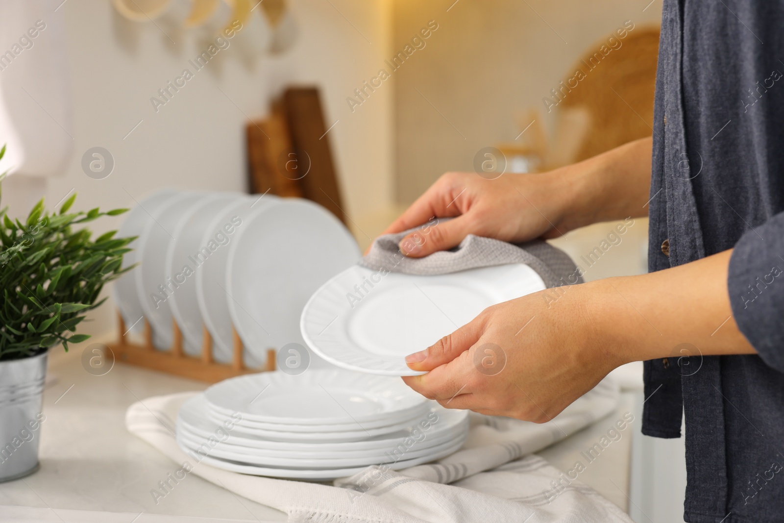 Photo of Woman wiping plate with towel in kitchen, closeup