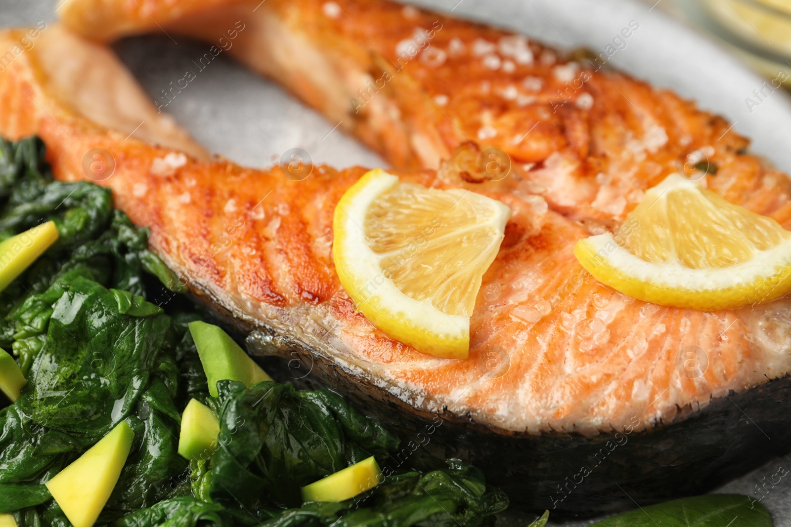 Photo of Tasty salmon with spinach on plate, closeup