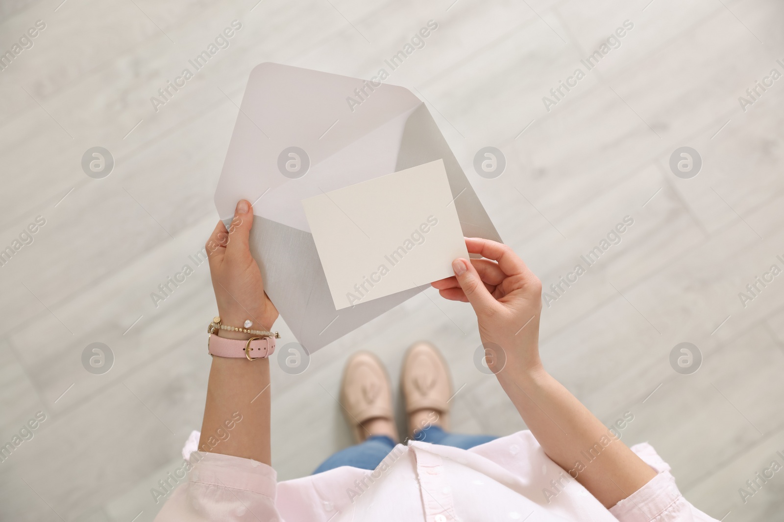 Photo of Woman holding envelope and blank greeting card indoors, top view