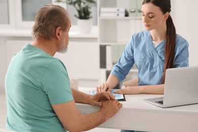 Professional orthopedist consulting patient at table in clinic