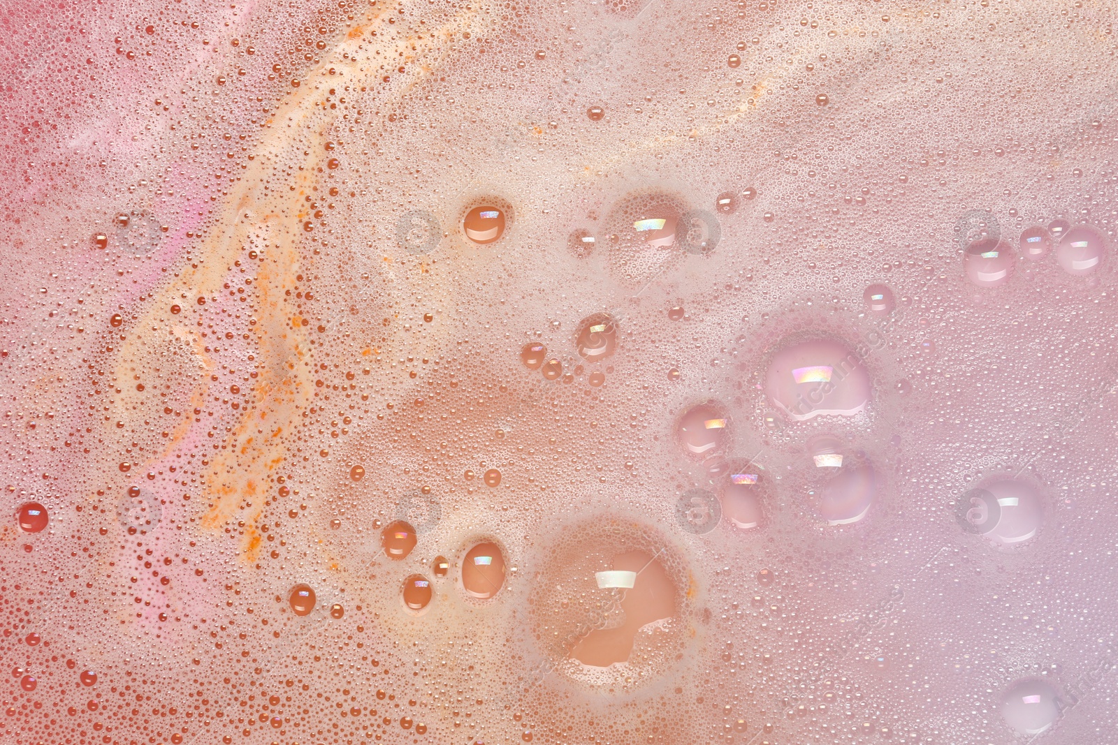 Photo of Colorful foam after dissolving bath bomb in water, closeup