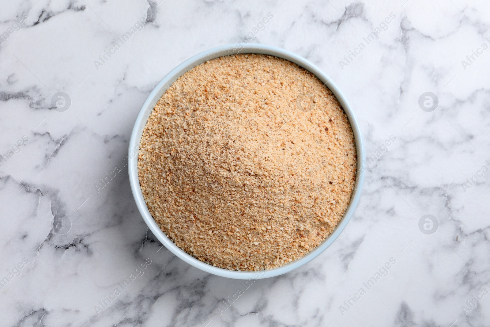 Photo of Fresh breadcrumbs in bowl on white marble table, top view