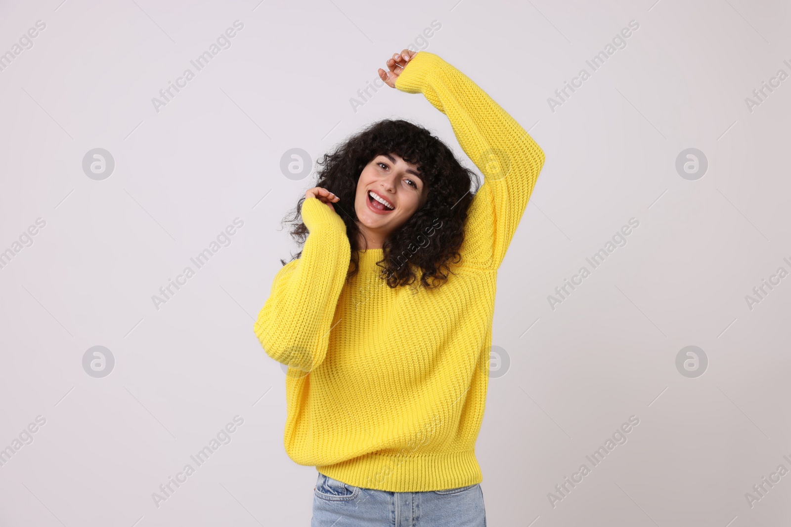 Photo of Happy young woman in stylish yellow sweater on white background