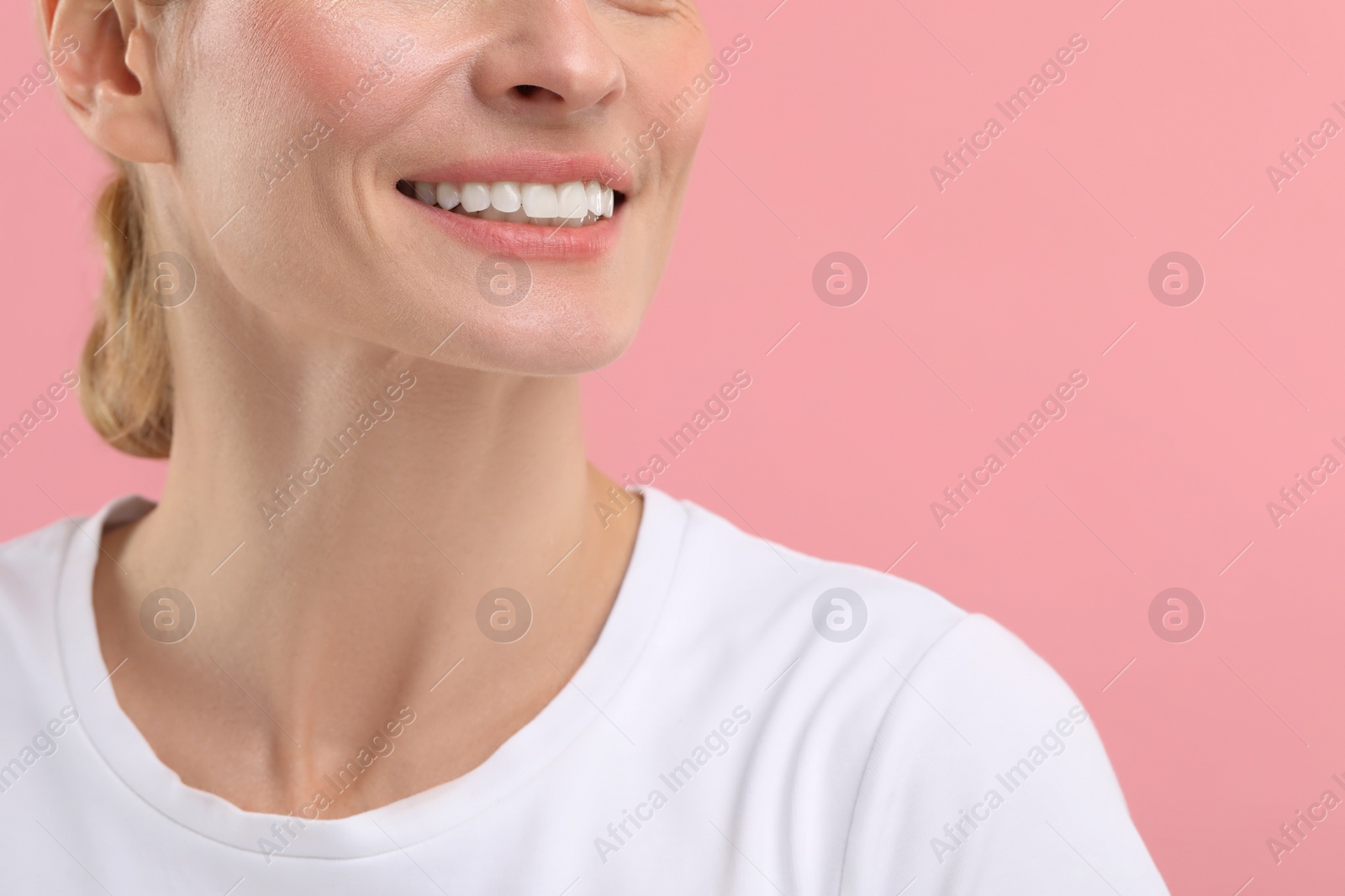 Photo of Woman with clean teeth smiling on pink background, closeup. Space for text