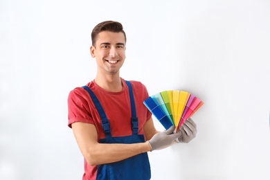 Male decorator holding color palette samples indoors