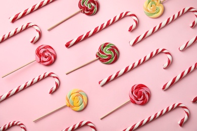 Photo of Flat lay composition with candy canes and lollipops on pink background