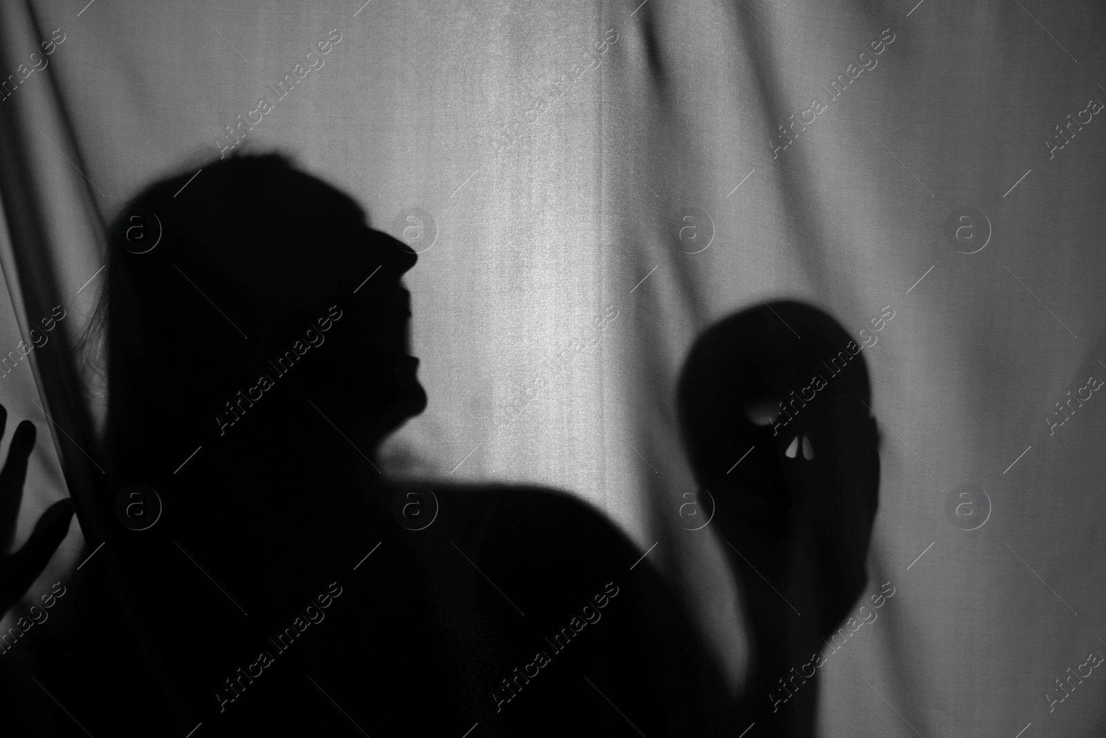 Photo of Silhouette of creepy ghost with skull behind grey cloth